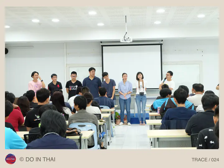 A group of speakers stands at the front of a classroom filled with seated participants.