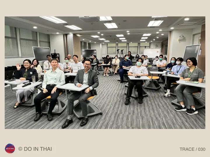 Participants pose while seated at rows of desks in a training room.
