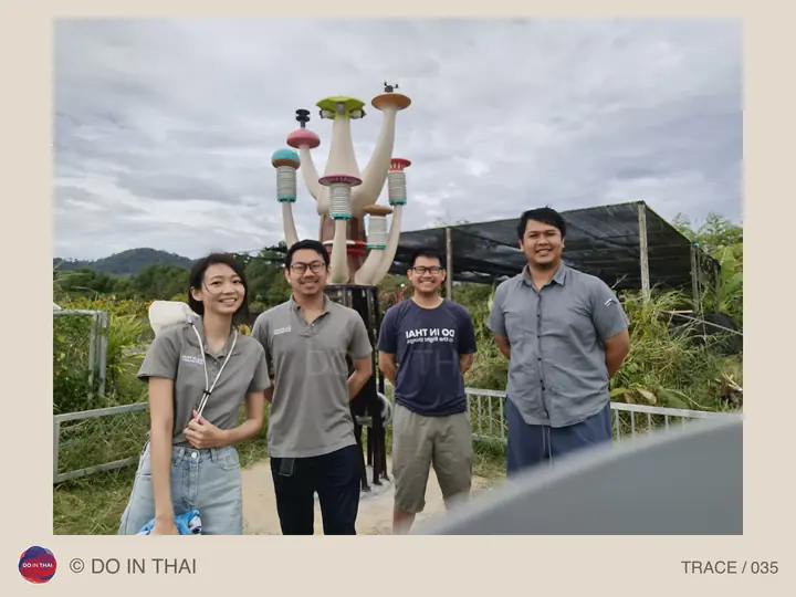 Four people pose beside colourful column-shaped instruments in a garden setting.